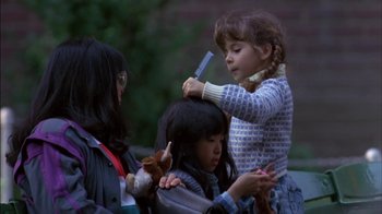 Movie still from “Crossing Delancey” (1988), directed by Joan Micklin Silver – A little girl getting her hair brushed by another girl; Medium shot, Over the shoulder angle