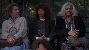 Movie still from “Crossing Delancey” (1988), directed by Joan Micklin Silver – A woman sitting next to another woman while holding a cell phone; Medium shot, High angle