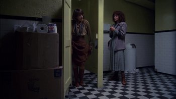 Two women standing next to each other in front of a bathroom door