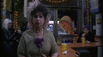 Movie still from “Crossing Delancey” (1988), directed by Joan Micklin Silver – An older woman in a costume sitting in front of a table; Close Up shot, Over the shoulder angle