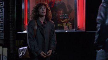Movie still from “Crossing Delancey” (1988), directed by Joan Micklin Silver – A woman standing in front of a building with lights; Medium shot, Over the shoulder angle
