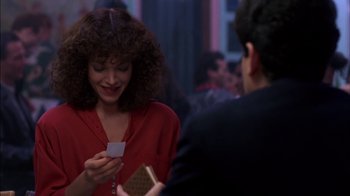 Movie still from “Crossing Delancey” (1988), directed by Joan Micklin Silver – A woman in a red shirt is holding a business card; Medium shot, Over the shoulder angle