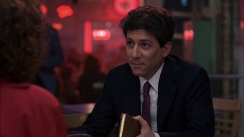 Movie still from “Crossing Delancey” (1988), directed by Joan Micklin Silver – A man sitting at a table holding a book in front of him; Close Up shot, Over the shoulder angle