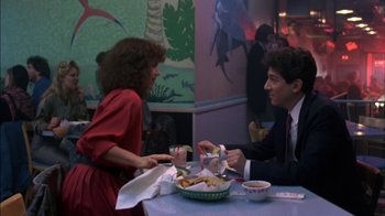 Movie still from “Crossing Delancey” (1988), directed by Joan Micklin Silver – A man and a woman sitting at a table with food; Medium shot, Over the shoulder angle