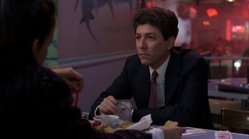 Movie still from “Crossing Delancey” (1988), directed by Joan Micklin Silver – A man sitting at a table with food in front of him; Medium shot, Over the shoulder angle