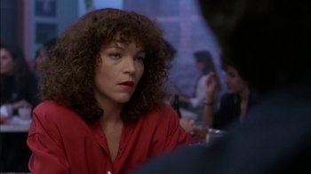 Movie still from “Crossing Delancey” (1988), directed by Joan Micklin Silver – A person sitting at a table in a room; Close Up shot, Over the shoulder angle