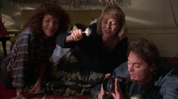 Movie still from “Crossing Delancey” (1988), directed by Joan Micklin Silver – A group of people sitting on a bed with a camera; Medium shot, Low angle