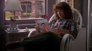 Movie still from “Crossing Delancey” (1988), directed by Joan Micklin Silver – A woman sitting in a chair reading a magazine; Medium shot, High angle