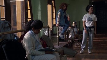 Movie still from “Crossing Delancey” (1988), directed by Joan Micklin Silver – A woman sitting on a chair reading a book; Wide shot, Low angle