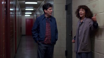 Movie still from “Crossing Delancey” (1988), directed by Joan Micklin Silver – A man and a woman standing next to each other in a hallway; Medium shot, Over the shoulder angle