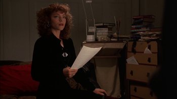 Movie still from “Crossing Delancey” (1988), directed by Joan Micklin Silver – A woman sitting in a chair holding a paper; Medium shot, Low angle