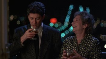 Movie still from “Crossing Delancey” (1988), directed by Joan Micklin Silver – A man and a woman standing next to each other holding wine glasses; Medium shot, Low angle