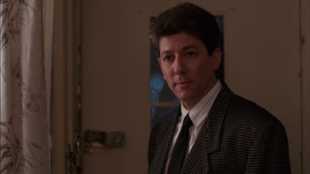 Movie still from “Crossing Delancey” (1988), directed by Joan Micklin Silver – A man wearing a suit and tie standing in front of a door; Close Up shot, Low angle