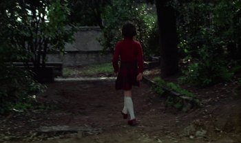 Movie still from “Cría Cuervos” (1976), directed by Carlos Saura – A girl in a red shirt is walking in the woods; Wide shot, High angle