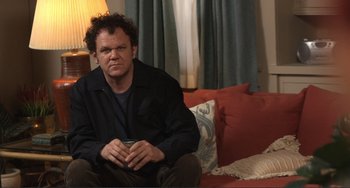 Movie still from “Cyrus” (2010), directed by Jay Duplass – A man sitting on a couch in front of a lamp; Medium shot, High angle