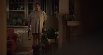 Movie still from “Cyrus” (2010), directed by Jay Duplass – A woman standing in a living room holding a gun; Wide shot, High angle