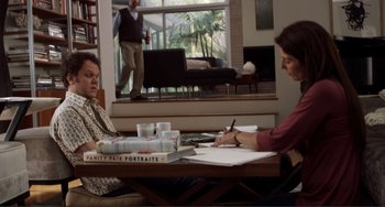 Movie still from “Cyrus” (2010), directed by Jay Duplass – Two people sitting at a table with papers and a book on it; Wide shot, Over the shoulder angle