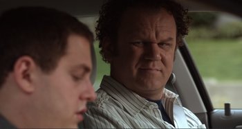 Movie still from “Cyrus” (2010), directed by Jay Duplass – A man sitting in the back seat of a car with another man; Close Up shot, Over the shoulder angle