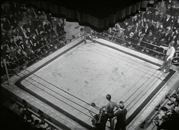 Movie still from “Daffy Duck in Hollywood” (1938), directed by Tex Avery – An old photo of a boxing match in a boxing ring; Extreme Wide shot, High angle