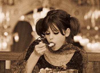 Movie still from “Daisies” (1966), directed by Vera Chytilová – A woman sitting at a table eating food from a bowl; Medium shot, High angle