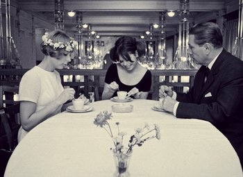 Movie still from “Daisies” (1966), directed by Vera Chytilová – A group of people sitting at a dinner table; Medium shot, High angle