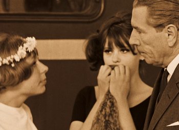 Movie still from “Daisies” (1966), directed by Vera Chytilová – A man and two women standing next to each other on a train; Medium shot, Over the shoulder angle