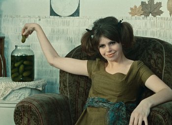 Movie still from “Daisies” (1966), directed by Vera Chytilová – A woman sitting in a chair holding a jar of pickles; Medium shot, Low angle