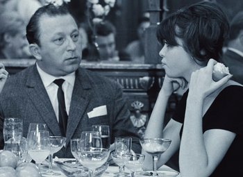 Movie still from “Daisies” (1966), directed by Vera Chytilová – A man and a woman sitting at a table with wine glasses in front of them; Medium shot, Over the shoulder angle