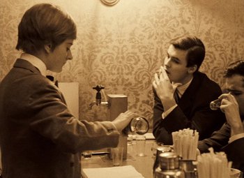 Movie still from “Daisies” (1966), directed by Vera Chytilová – A man and a woman sitting in front of a mirror; Medium shot, High angle