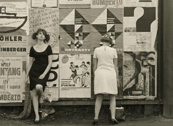 Movie still from “Daisies” (1966), directed by Vera Chytilová – Two women are standing in front of a wall of posters; Medium shot, Low angle