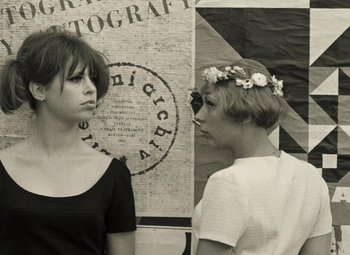 Movie still from “Daisies” (1966), directed by Vera Chytilová – Two young women standing next to each other in front of a wall; Close Up shot, High angle
