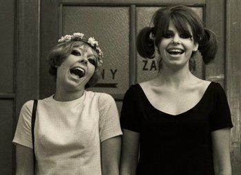 Movie still from “Daisies” (1966), directed by Vera Chytilová – Two young women standing next to each other and laughing; Medium shot, Low angle