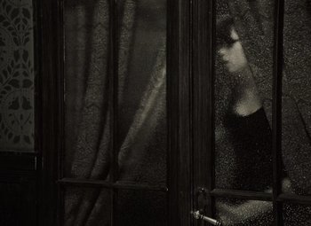 Movie still from “Daisies” (1966), directed by Vera Chytilová – A woman looking out a window through a curtain; Medium shot, Low angle