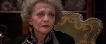 Movie still from “Damien: Omen II” (1978), directed by Mike Hodges – An older woman sitting on a couch looking off to the side; Close Up shot, High angle