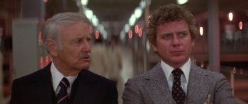 Movie still from “Damien: Omen II” (1978), directed by Mike Hodges – Two men in suits and ties standing next to each other; Close Up shot, Low angle