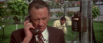 Movie still from “Damien: Omen II” (1978), directed by Mike Hodges – An older man talking on a phone while another man watches; Close Up shot, Low angle