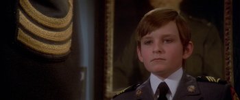 Movie still from “Damien: Omen II” (1978), directed by Mike Hodges – A young boy in a military uniform looking at the camera; Close Up shot, Low angle
