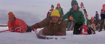 Movie still from “Damien: Omen II” (1978), directed by Mike Hodges – An old man is laying in the snow while others watch; Medium shot, Low angle