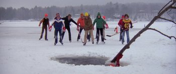 Movie still from “Damien: Omen II” (1978), directed by Mike Hodges – A group of people playing a game of ice hockey on a frozen lake; Extreme Wide shot, High angle