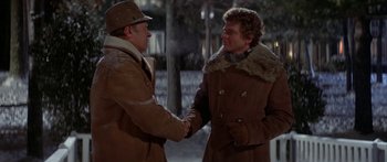 Movie still from “Damien: Omen II” (1978), directed by Mike Hodges – Two men shaking hands in the snow outside; Medium shot, Over the shoulder angle
