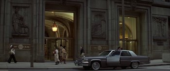 Movie still from “Damien: Omen II” (1978), directed by Mike Hodges – A car parked in front of a building on a street; Extreme Wide shot, Low angle