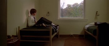 Movie still from “Damien: Omen II” (1978), directed by Mike Hodges – A young man sitting on a bed in a room; Wide shot, High angle