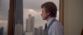 Movie still from “Damien: Omen II” (1978), directed by Mike Hodges – A man with curly hair wearing a vest and a tie; Close Up shot, Over the shoulder angle