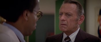 Movie still from “Damien: Omen II” (1978), directed by Mike Hodges – An older man wearing a suit and tie looking at a younger man wearing glasses; Close Up shot, Over the shoulder angle