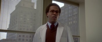 Movie still from “Damien: Omen II” (1978), directed by Mike Hodges – A man in a white lab coat standing in front of a window; Close Up shot, Low angle