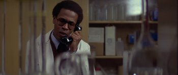 Movie still from “Damien: Omen II” (1978), directed by Mike Hodges – A man talking on a phone while wearing a white suit; Close Up shot, Low angle