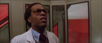 Movie still from “Damien: Omen II” (1978), directed by Mike Hodges – A man in a white lab coat wearing glasses; Close Up shot, Low angle