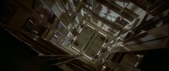 Movie still from “Damien: Omen II” (1978), directed by Mike Hodges – Looking up at the ceiling of a building with lights on it; Extreme Wide shot, Overhead angle