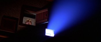 Movie still from “Damien: Omen II” (1978), directed by Mike Hodges – A blue light shining on a wall in a dark room; Medium shot, Low angle