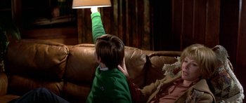 Movie still from “Damien: Omen II” (1978), directed by Mike Hodges – A little boy that is sitting on a couch; Medium shot, Over the shoulder angle